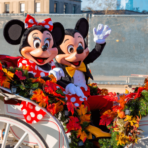 Mickey y Minnie Mouse viajan en un carruaje abierto en el desfile anual del Día de Acción de Gracias.
