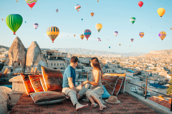 Feliz pareja joven durante el amanecer viendo globos de aire caliente en Cappadocia