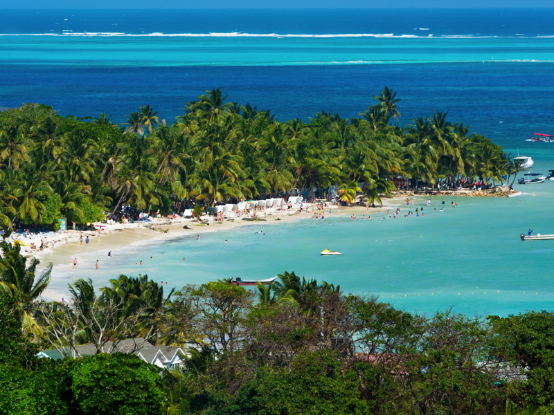 Landscape of the beach of San Andres island and Providencia Archipelago in Colombia with blue ocean and green palms and vegetation with boats and tourists