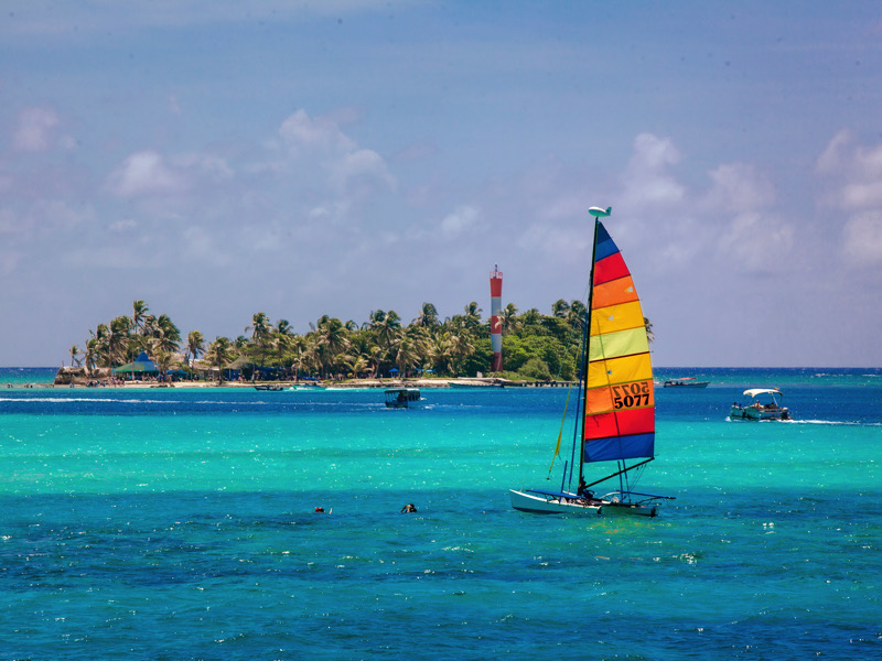 Small colorful sailboat sailing in the blue and transparent waters of the island of San Andres.