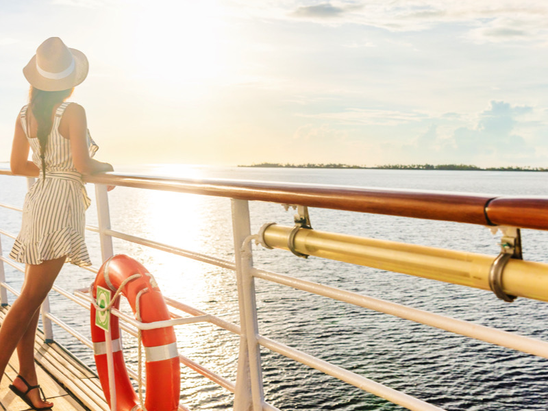 Luxury cruise ship travel elegant tourist woman watching sunset on balcony deck of Europe mediterranean cruising destination. Summer vacation cruiseship sailing away on holiday.