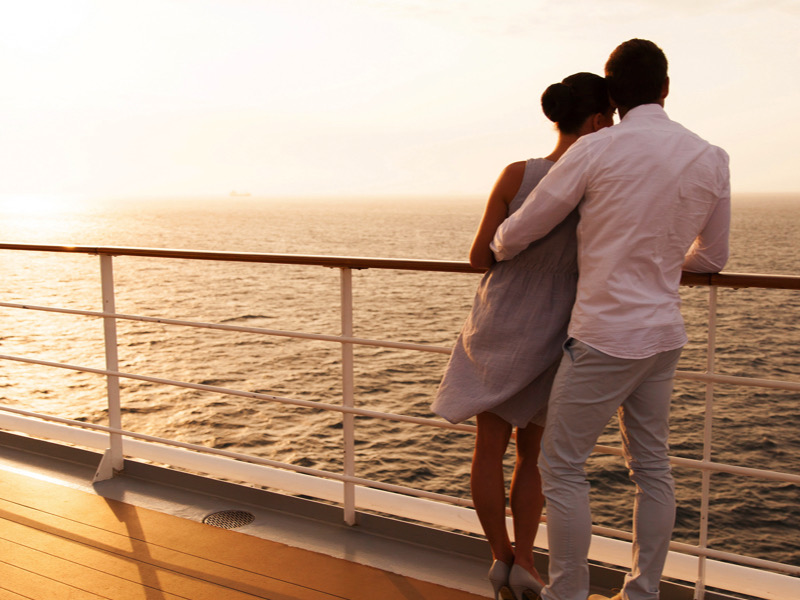 back view of young couple hugging at sunset on cruise ship
