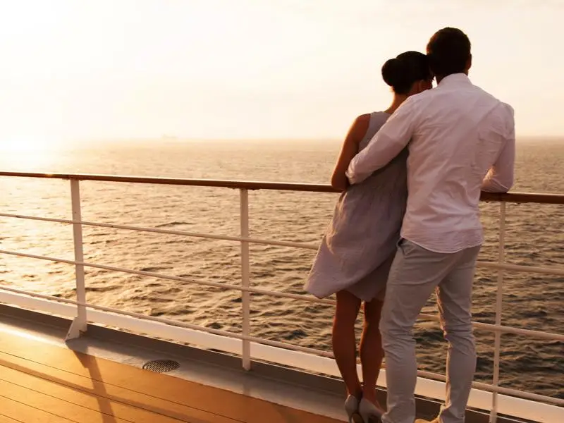 back view of young couple hugging at sunset on cruise ship